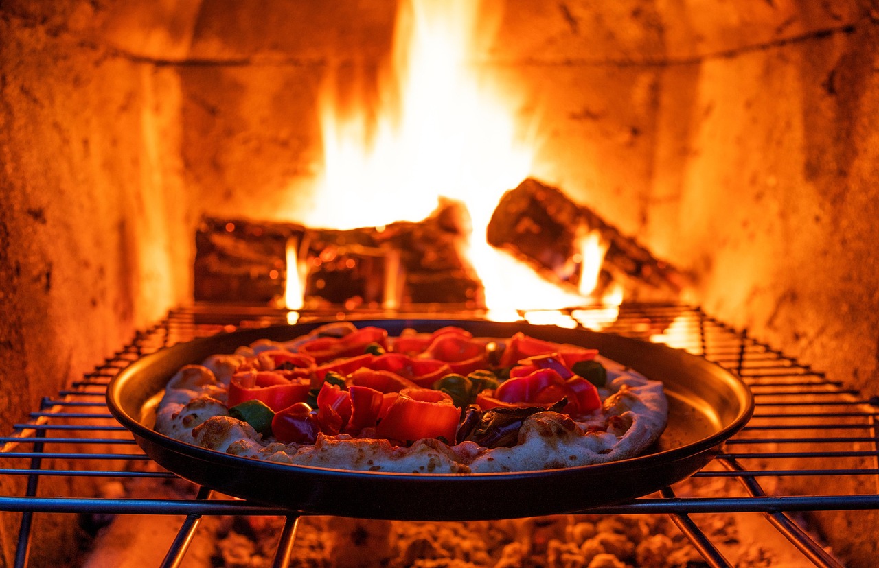 Flames roaring in the wood-fired oven behind a dish baking on the rack